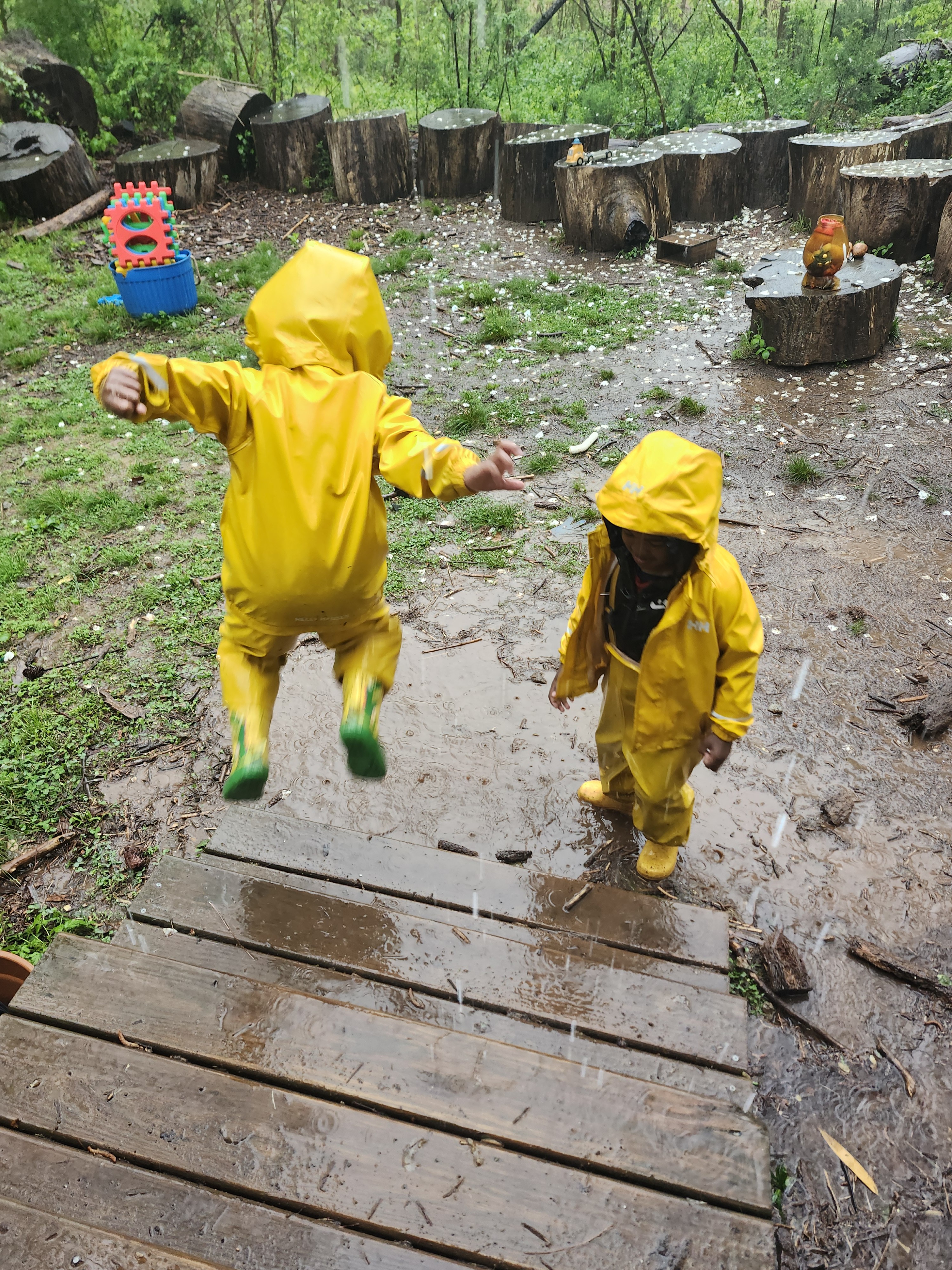 children in yellow rainsuits jumping in puddles